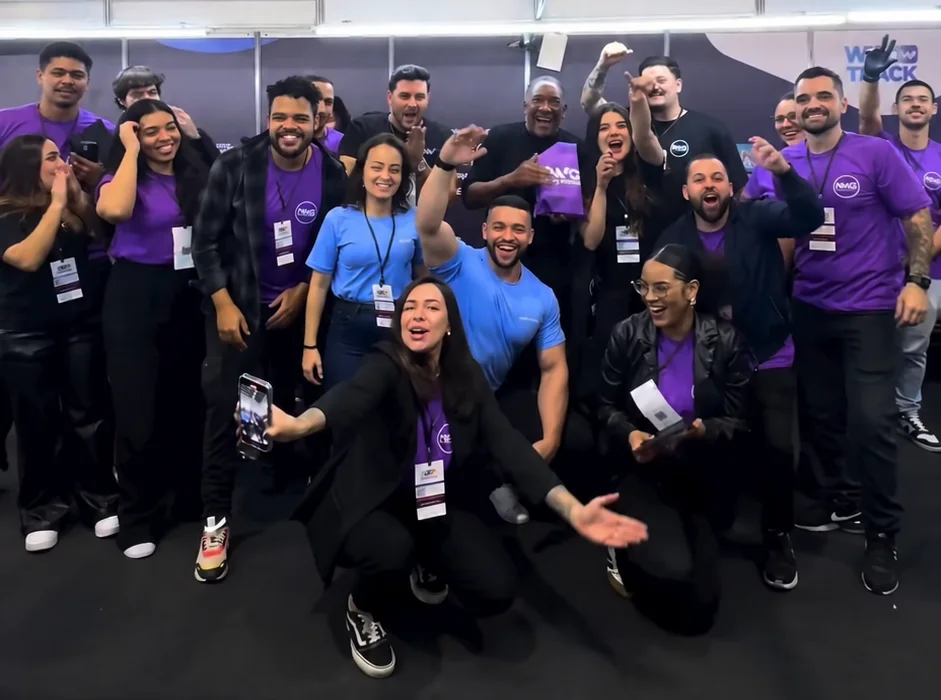 Time da Neway reunido com camisetas roxas da marca em um evento, comemorando
